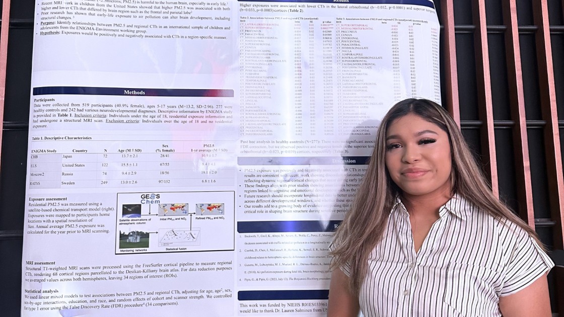 Student smiling in front of her research poster