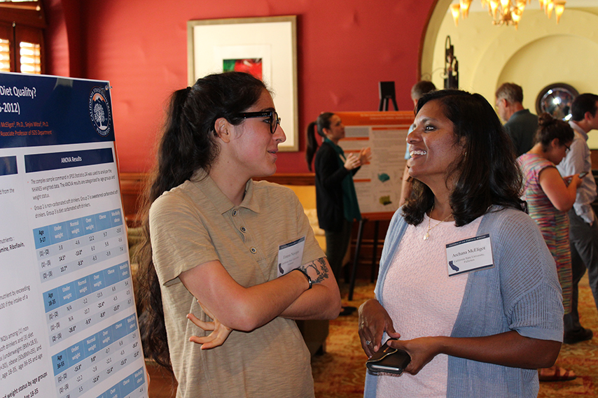 Dr. McEligot and a student talking, standing by a research poster